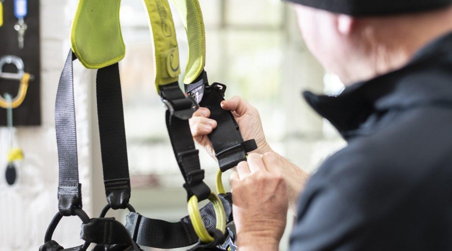 Mann kontrolliert Auffanggurt  – Toprope